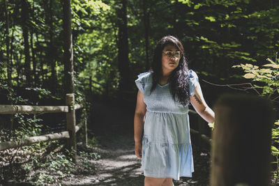 Portrait of young woman standing against trees