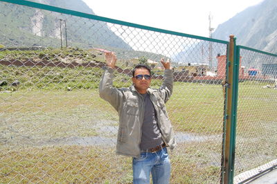 Full length of man standing by chainlink fence