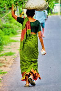 Rear view of woman walking on road