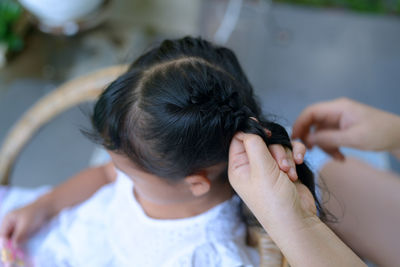 Mother braiding her daughter's hair outdoor.