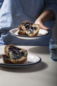 Close-up of hand holding cake in plate over table