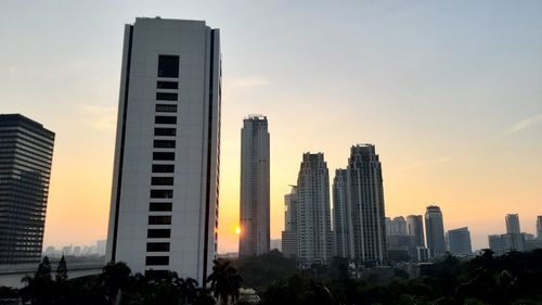 Modern buildings in city against sky during sunset