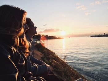 Woman looking at sea against sky during sunset