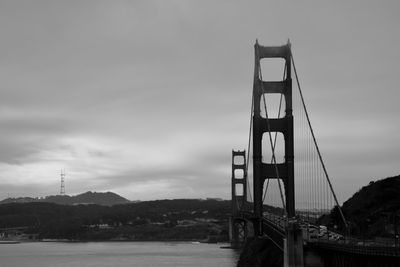 Bridge over river against cloudy sky