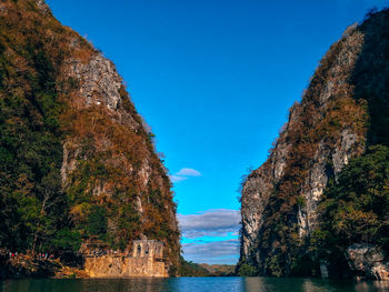 Scenic view of sea and mountains against clear blue sky