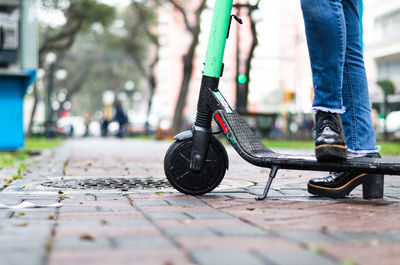 Low section of woman with segway standing on footpath