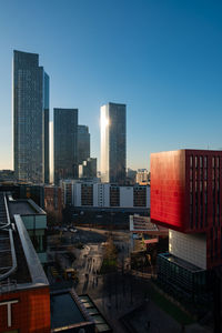 Modern buildings in city against clear blue sky