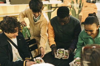 High angle view of happy friends arranging food boxes on table