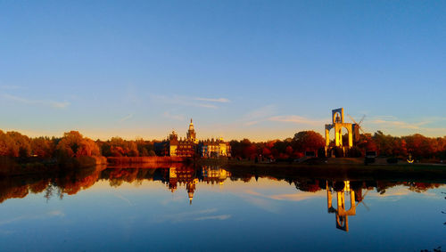 Reflection of building in lake against sky in city