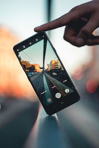 Close-up of person holding mobile phone at sunset