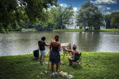 Rear view of people on lake against trees