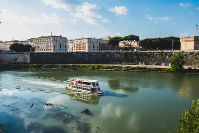 Bridge over river by buildings in city against sky
