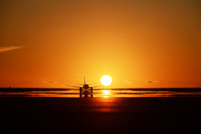 Silhouette beach against sky during sunset