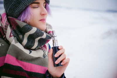 Close-up of girl holding smart phone during winter