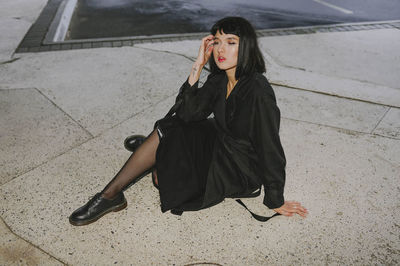 Woman sitting on the sidewalk in a black cloak