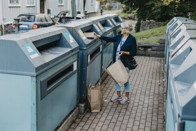 Woman putting cardboard in recycling bin