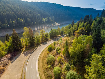 Road amidst trees and mountains against sky