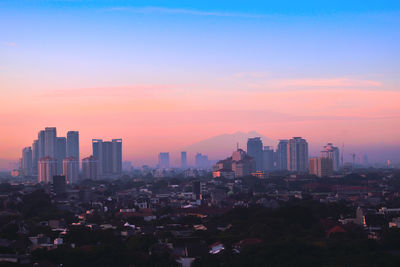 Modern buildings against sky during sunset