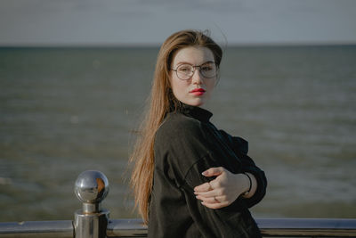 Portrait of young woman standing against sea