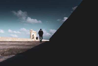 Rear view of people walking on road against sky