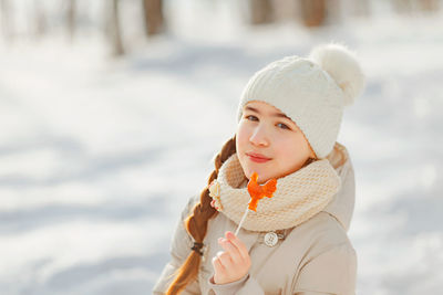 Portrait of teenage girl holding candy outdoors during winter