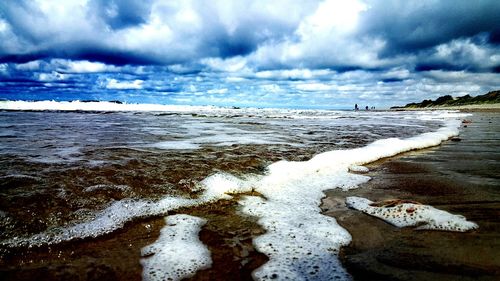 Scenic view of beach against cloudy sky