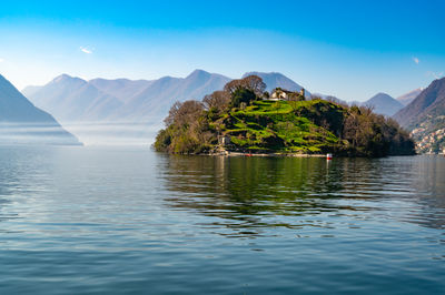 Comacina island, photographed in autumn, with trees, boats and piers around.