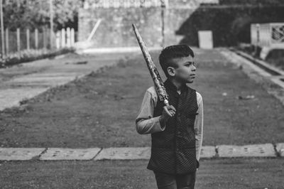 Boy holding umbrella while standing on field