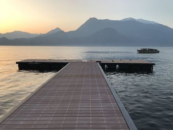 Pier over lake como against mountain sky at sunset