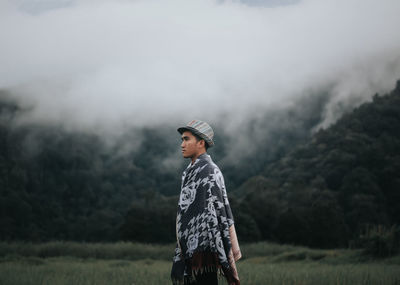 Man wrapped in sheet while standing against sky