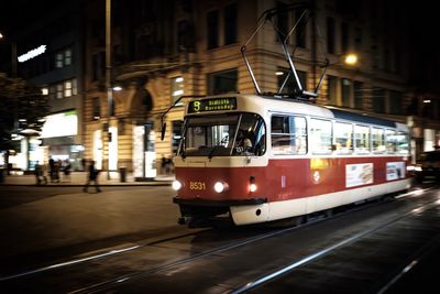 Tram on illuminated city street at night