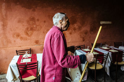 Side view of a man walking by chairs and tables