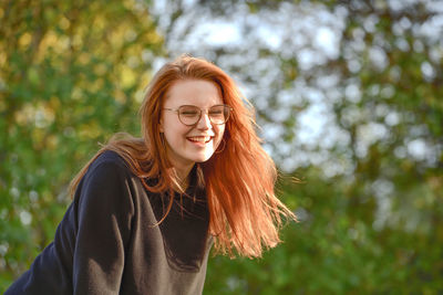 Portrait of young woman standing against plants