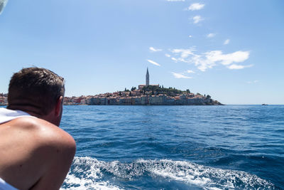 Rear view of man in sea against blue sky