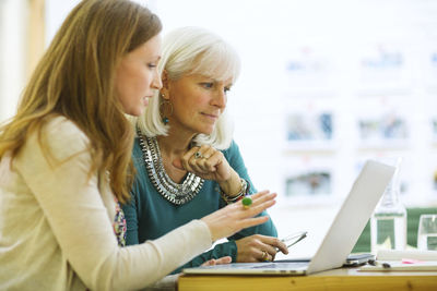 Female coworkers doing research on laptop computer in board room