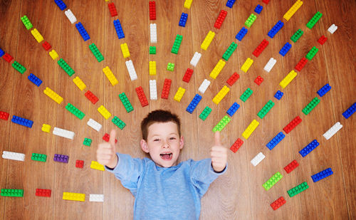Portrait of a cheerful child boy in a blue sweater lying on the floor 