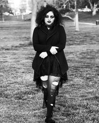 Portrait of gothic woman walking on grassy field