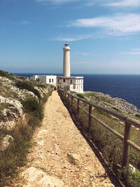 Lighthouse amidst sea and buildings against sky