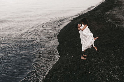 A diverse of lovers a man and a woman embrace under a blanket on the ocean at night outdoor