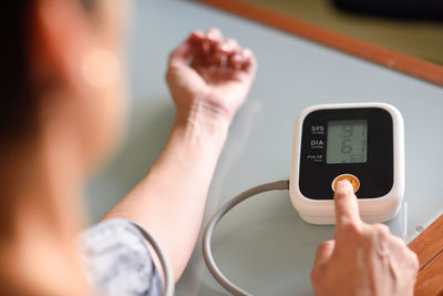 Cropped hands of mature woman examining blood pressure at home