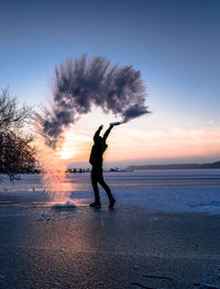 Silhouette man on beach against sky during sunset