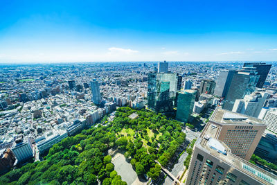 High angle view of modern buildings in city against blue sky