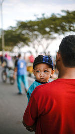 Rear view of man standing with baby boy on street