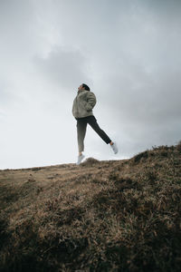 Rear view of man standing on field against sky