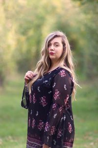 Young woman standing against tree