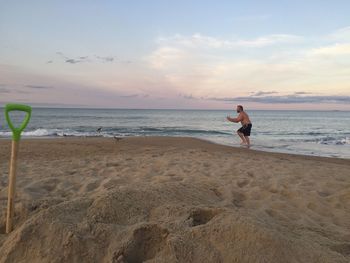 Man at beach against sky during sunset