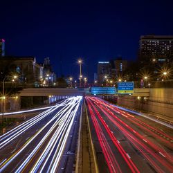 Light trail on highway in city against sky