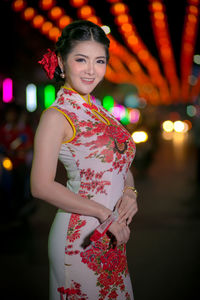 Portrait of young woman wearing cheongsam during festival at night