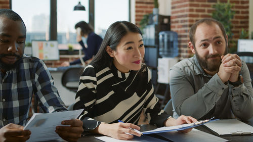 Portrait of smiling friends using smart phone while sitting on table