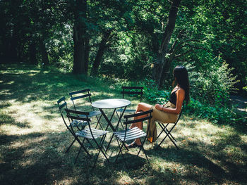 Woman sitting on chair at table in forest